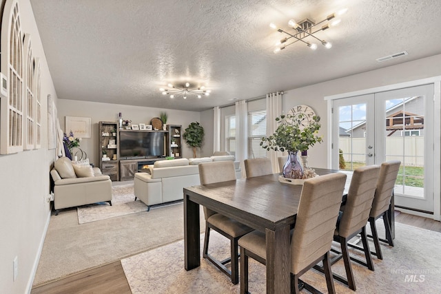 dining space featuring a textured ceiling, light hardwood / wood-style flooring, and french doors