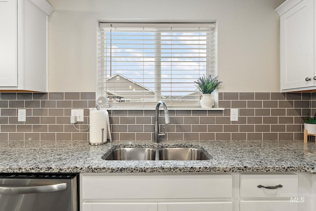 kitchen featuring decorative backsplash, white cabinetry, sink, and stainless steel dishwasher