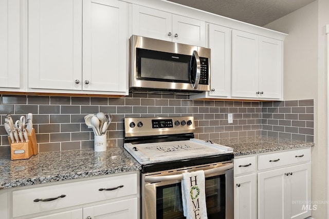 kitchen featuring white cabinets, stainless steel appliances, light stone counters, and tasteful backsplash