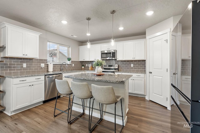 kitchen featuring wood-type flooring, white cabinetry, and stainless steel appliances