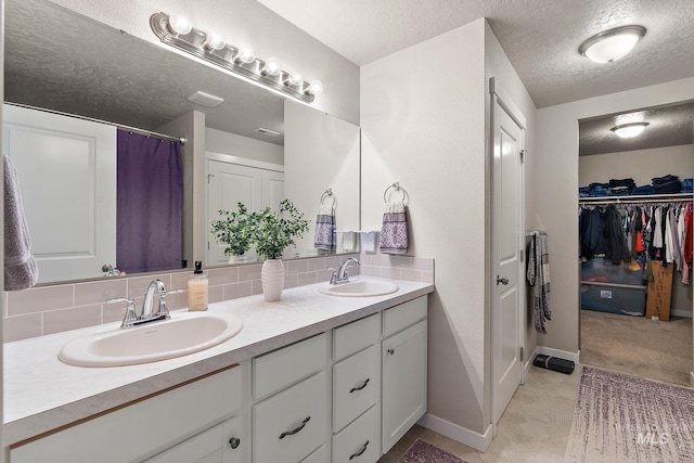 bathroom with a textured ceiling, vanity, and backsplash