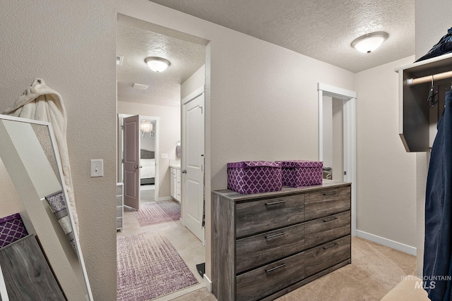 corridor with a textured ceiling and light colored carpet