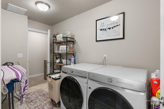 laundry room with washing machine and dryer, a textured ceiling, and light carpet