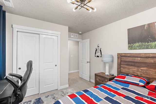 carpeted bedroom featuring a closet, a textured ceiling, and a notable chandelier