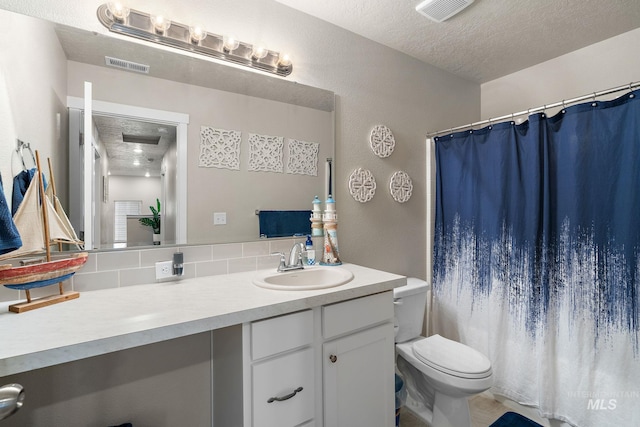 bathroom with vanity, toilet, and a textured ceiling