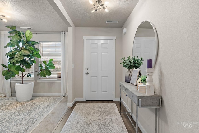 entrance foyer featuring a chandelier, a textured ceiling, and hardwood / wood-style flooring