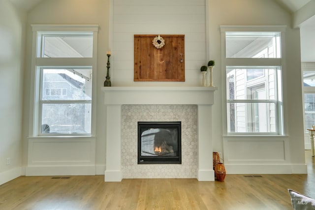 details with wood-type flooring and a tiled fireplace