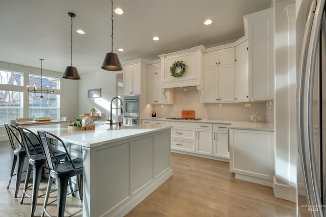 kitchen featuring white cabinets, stainless steel appliances, and hanging light fixtures