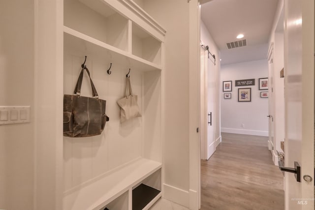 mudroom featuring a barn door and light hardwood / wood-style flooring