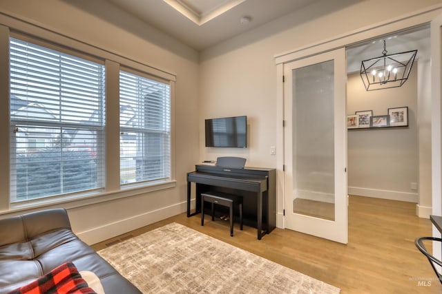 sitting room featuring french doors, light hardwood / wood-style flooring, and an inviting chandelier