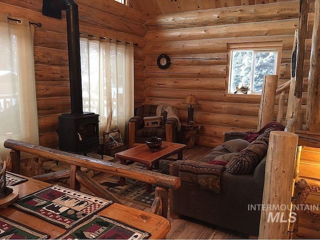 interior space with lofted ceiling, a wood stove, hardwood / wood-style floors, and rustic walls