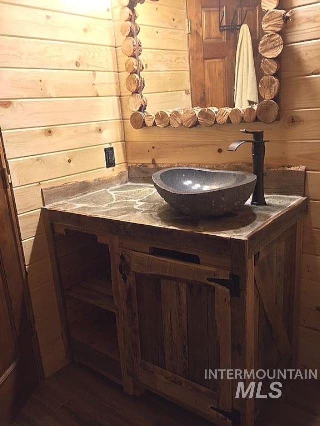 bathroom with vanity, wood-type flooring, and wood walls