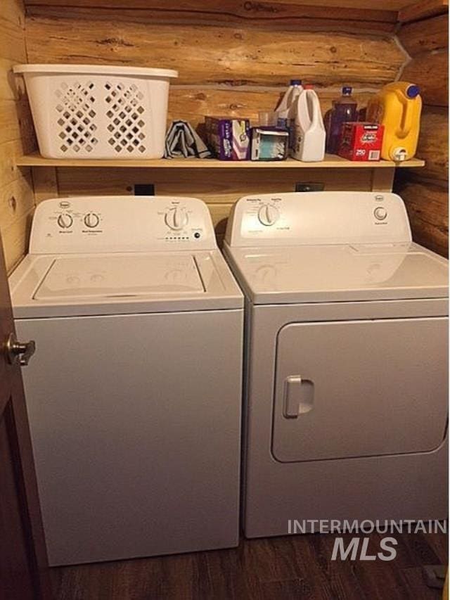 washroom featuring separate washer and dryer, dark hardwood / wood-style floors, and rustic walls