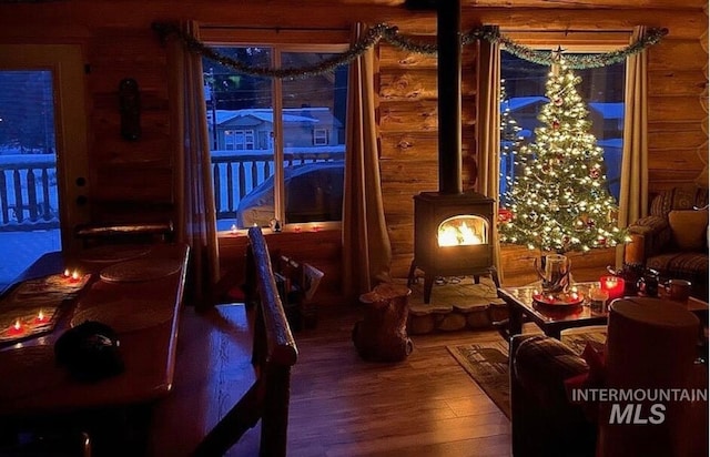 living area with wood-type flooring, a wood stove, and log walls