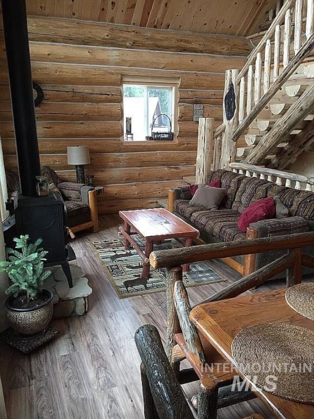 living room with hardwood / wood-style flooring, wood ceiling, rustic walls, and a wood stove