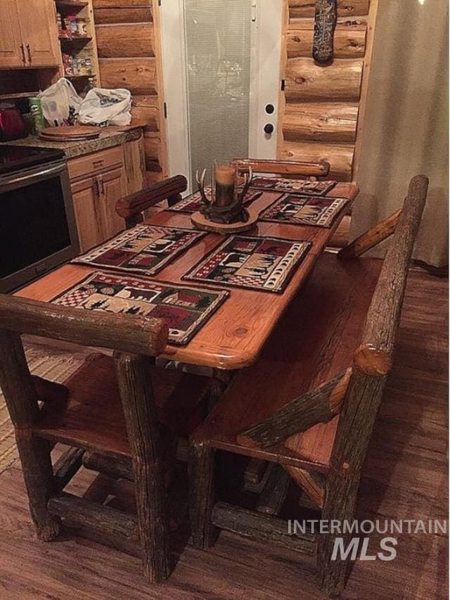 dining space with dark wood-type flooring and log walls