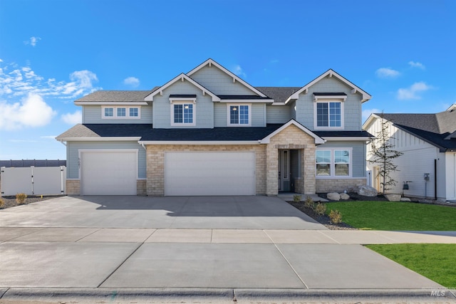 craftsman inspired home with fence, concrete driveway, a front lawn, a garage, and stone siding