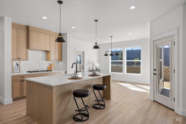 5687 S Snowden Ave, Meridian, ID 83642 - kitchen featuring gas stovetop, a sink, decorative backsplash, light countertops, and light wood-style floors