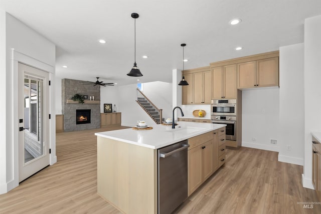 5687 S Snowden Ave, Meridian, ID 83642 - kitchen featuring light countertops, light wood-style flooring, a fireplace, stainless steel appliances, and a sink
