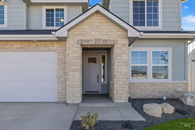 5687 S Snowden Ave, Meridian, ID 83642 - doorway to property with stone siding, driveway, a shingled roof, and a garage