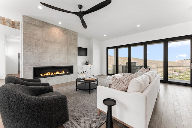 4135 N Hawkeye Pl, Boise, ID 83703 - living area with light wood-style flooring, ceiling fan, recessed lighting, a tiled fireplace, and baseboards