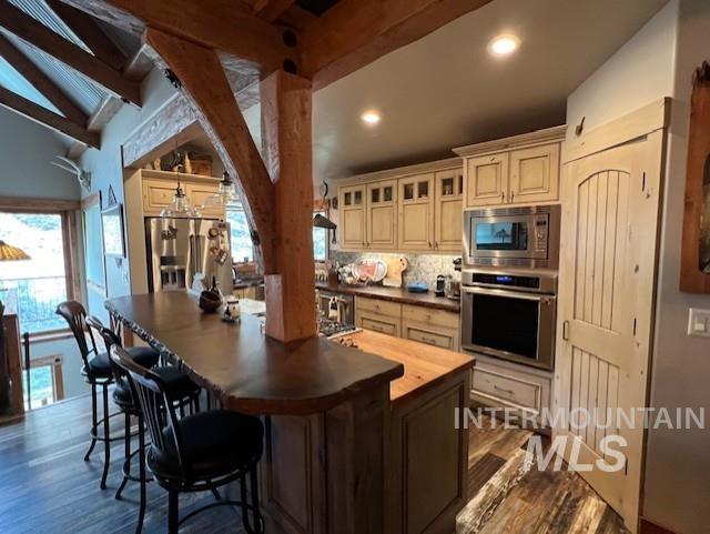 kitchen with backsplash, stainless steel appliances, hardwood / wood-style floors, lofted ceiling with beams, and butcher block countertops