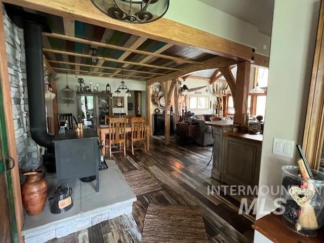 interior space featuring beamed ceiling, dark wood-type flooring, a wood stove, and a chandelier