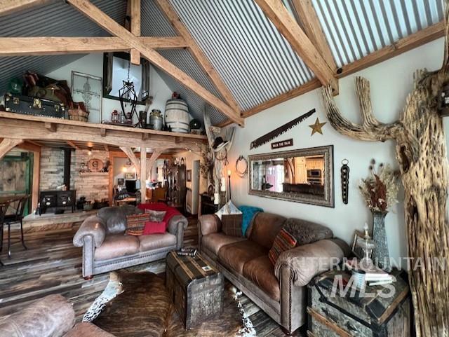 living room with hardwood / wood-style flooring, beam ceiling, high vaulted ceiling, and a wood stove