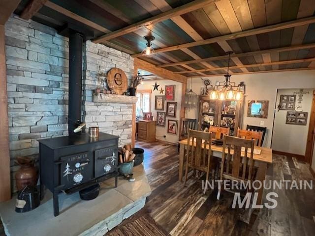 dining area with wood-type flooring, ceiling fan with notable chandelier, and a wood stove