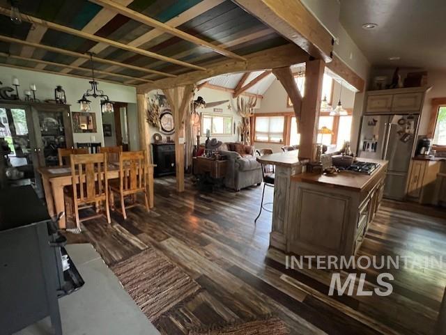 interior space with a notable chandelier, dark wood-type flooring, and lofted ceiling with beams