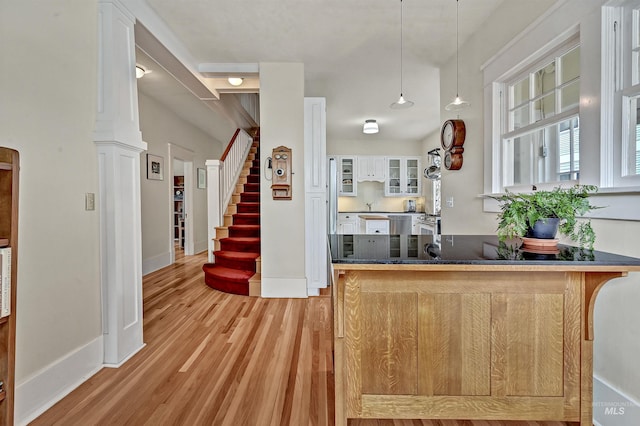 1707 W Resseguie St, Boise, ID 83702 - kitchen with light wood-type flooring, glass insert cabinets, a peninsula, and white cabinetry