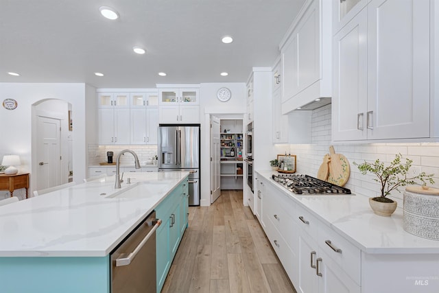 kitchen with light stone countertops, appliances with stainless steel finishes, sink, and white cabinets