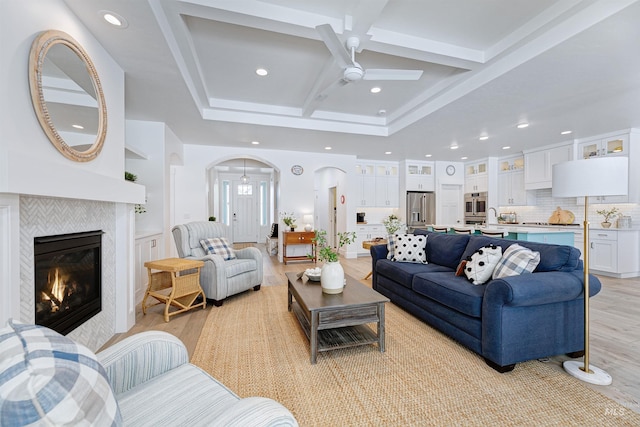 living room with a fireplace, sink, coffered ceiling, beam ceiling, and light hardwood / wood-style flooring