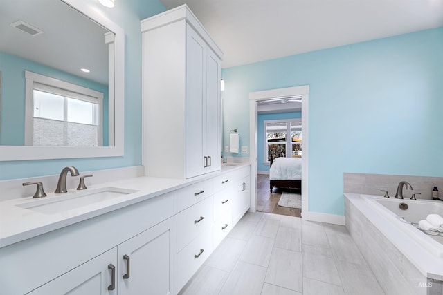 bathroom featuring tiled tub and vanity