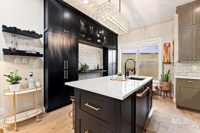 476 E Thurman Mill St, Garden City, ID 83714 - kitchen featuring an island with sink, light wood-style flooring, tasteful backsplash, light countertops, and dark cabinetry