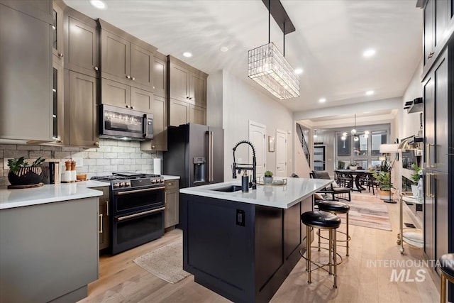 476 E Thurman Mill St, Garden City, ID 83714 - kitchen featuring appliances with stainless steel finishes, an island with sink, decorative backsplash, light wood finished floors, and a sink