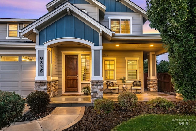 exterior entry at dusk featuring a garage and a porch