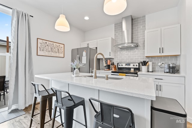 2114 W Claira Rd, Nampa, ID 83651 - kitchen featuring wall chimney range hood, tasteful backsplash, a breakfast bar, white cabinetry, and appliances with stainless steel finishes