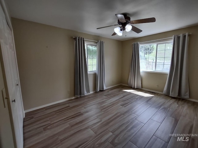 spare room with ceiling fan, plenty of natural light, and light wood-type flooring