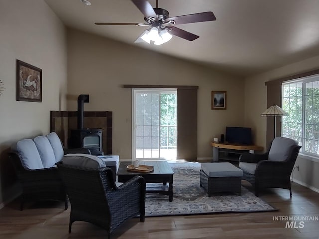 living room with lofted ceiling, wood-type flooring, ceiling fan, and a wood stove