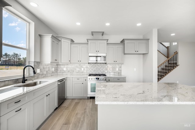 kitchen featuring appliances with stainless steel finishes, sink, and light stone countertops