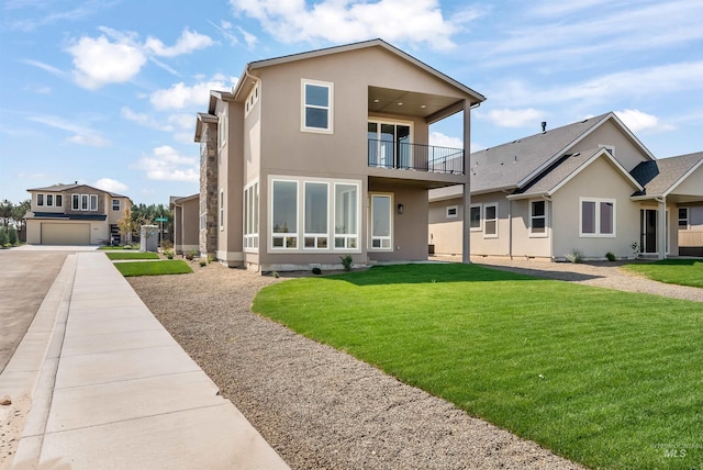 rear view of house with a balcony and a lawn