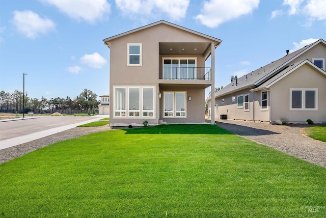 back of house featuring a yard and a balcony