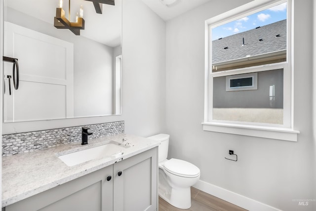 bathroom with toilet, vanity, and tasteful backsplash