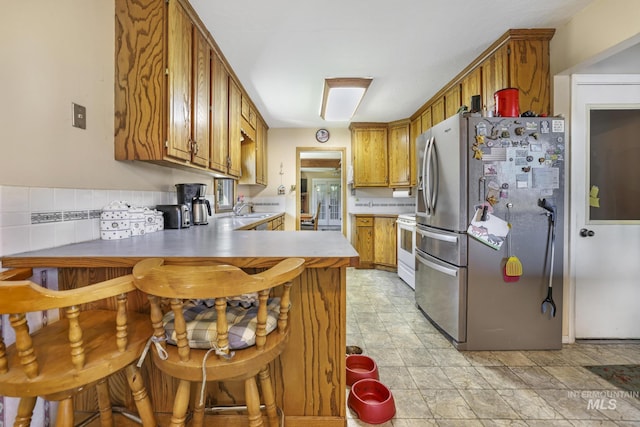 3242 S 2000 E, Wendell, ID 83355 - kitchen with a sink, white range with electric stovetop, freestanding refrigerator, a peninsula, and brown cabinetry