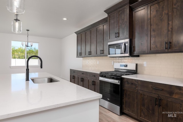 8900 W Snow Wolf Dr, Star, ID 83669 - kitchen featuring appliances with stainless steel finishes, a sink, hanging light fixtures, light stone counters, and tasteful backsplash