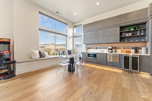 kitchen featuring a mountain view, gray cabinets, light wood-type flooring, beverage cooler, and sink