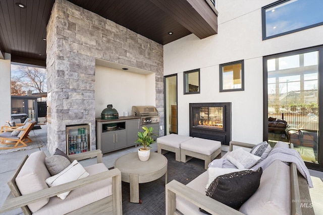 view of patio featuring an outdoor kitchen, an outdoor living space with a fireplace, and a grill