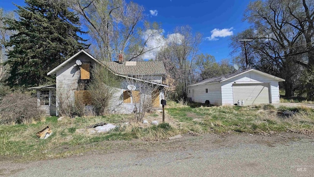 view of side of home featuring a garage, a chimney, and an outdoor structure