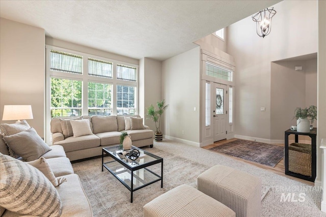 living area featuring healthy amount of natural light, baseboards, and a textured ceiling